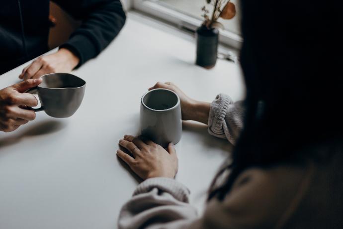 Mujer en camisa de manga larga negra con taza de cerámica negra tomando un café con un cliente